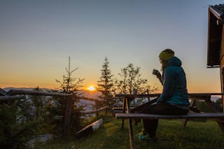 Woman drinking coffee in the mountains during sunrise